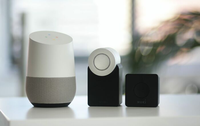 white and gray Google smart speaker and two black speakers