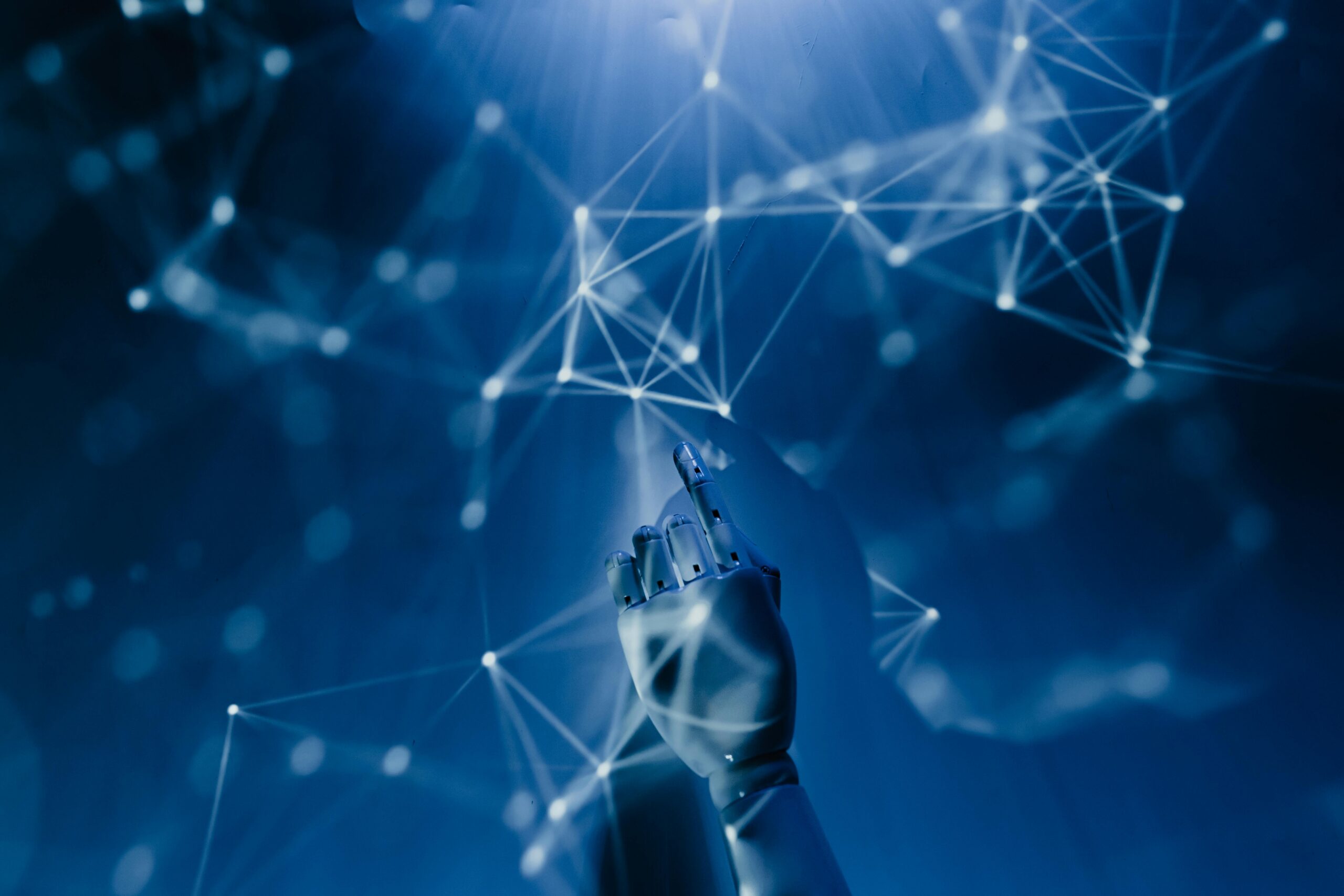 Free A robotic hand reaching into a digital network on a blue background, symbolizing AI technology. Stock Photo