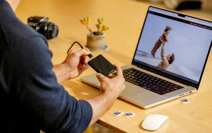 A man sitting at a table with a laptop and cell phone